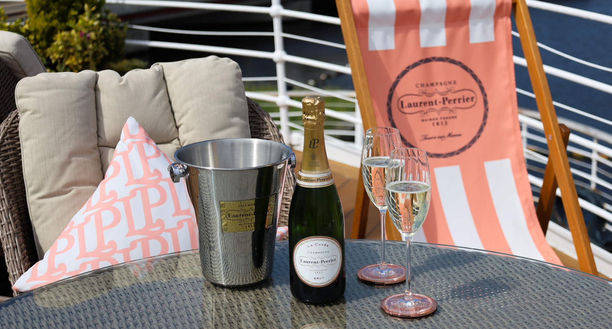 Two glasses of champagne and a bottle on a ship deck. 